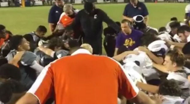 Community members and football players pray over an injury.