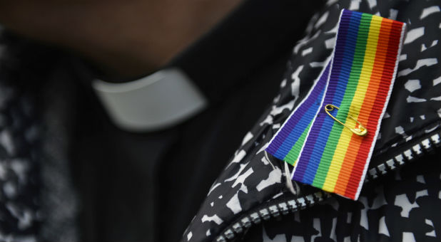 A priest wears a rainbow ribbon during a vigil against Anglican homophobia, outside the General Synod of the Church of England in London