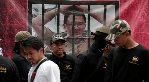 Muslim protesters stand near a picture of Jakarta's incumbent governor Basuki Tjahaja Purnama, also known as Ahok, outside a court at the blasphemy trial of the governor in Jakarta, Indonesia