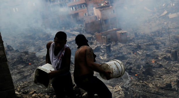 Residents pour water from their houses as they try to extinguish a fire at Paraisopolis slum in Sao Paulo, Brazil