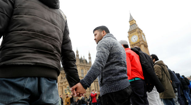 People hold hands on Westminster Bridge during an event to mark one week since a man drove his car into pedestrians and then stabbed a police officer in London