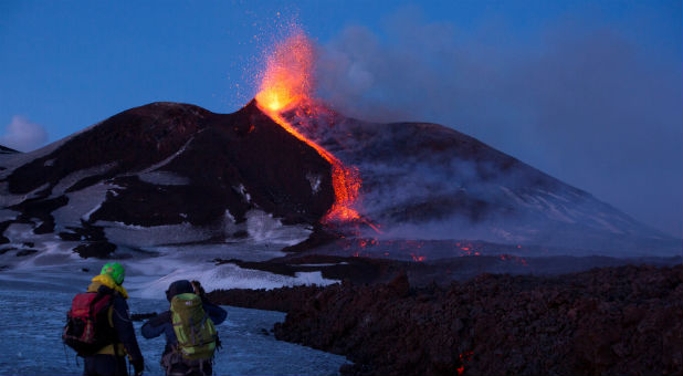 Volcano guides stand in front of Italy's Mount Etna, Europe's tallest and most active volcano, as it spews lava during an eruption on the southern island of Sicily, Italy Feb. 28