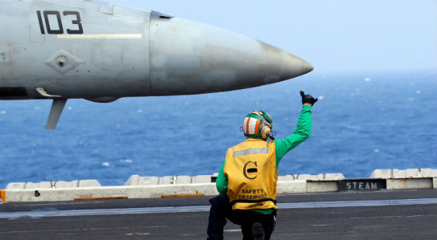 A flight deck crew gives a hand signal to the pilot of a U.S. Navy F18 fighter jet on aircraft carrier USS Carl Vinson during a routine exercise in the South China Sea