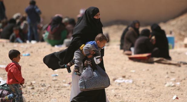 A woman, who fled from Raqqa city, carries a child in al-Mahmudli village, west of Raqqa, Syria