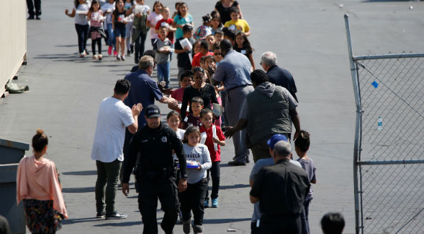 Students who were evacuated after a shooting at North Park Elementary School walk past well-wishers to be reunited with their waiting parents at a high school in San Bernardino, California