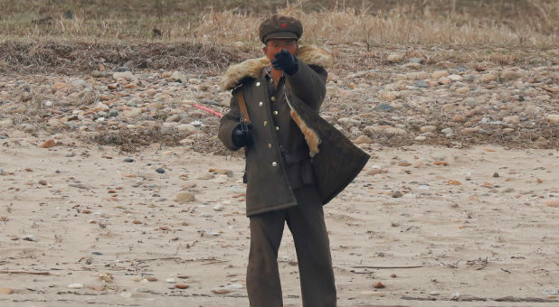 A North Korean soldier gestures from the North Korean side of the Yalu River towards a Chinese boat carrying tourists near Sinuiju, North Korea