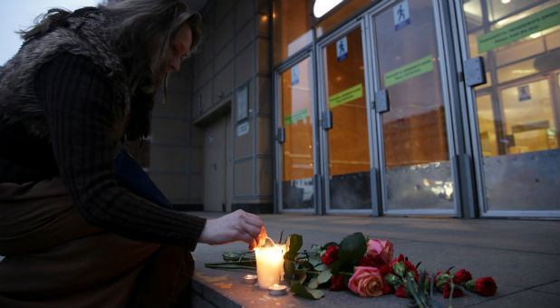 A woman lights a candle during a memorial service for victims of a blast in St. Petersburg metro, outside Spasskaya metro station in St. Petersburg, Russia