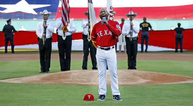 Texas Rangers third base coach Tony Beasley sings the national anthem before the team's opening-day game against the Cleveland Indians