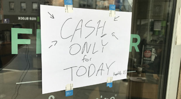 A sign informing customers that electronic payments are not functioning is seen at the entrance of a Starbucks coffee shop