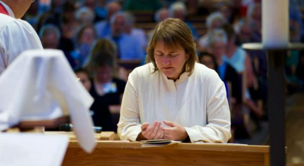 Bishop Karen Oliveto, the first openly gay bishop in The United Methodist Church, kneels during the consecration service held on July 16, 2016, at Paradise Valley United Methodist Church in Scottsdale, Arizona.