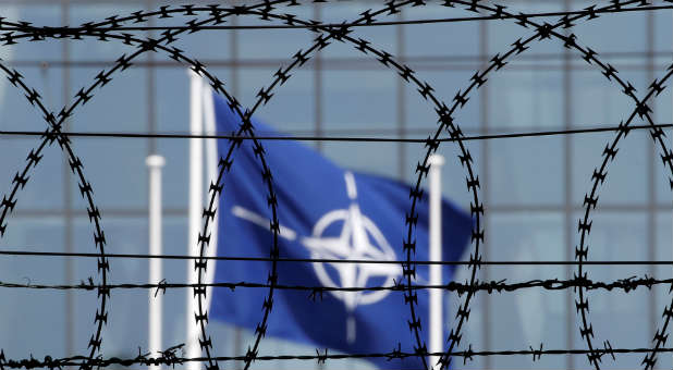 The NATO flag is seen through barbed wire as it flies in front of the new NATO Headquarters in Brussels, Belgium.