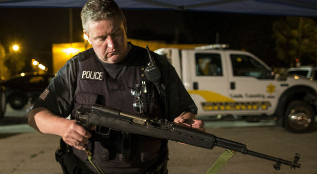 A Cook County Sheriff police officer holds an assault rifle recovered in an alley in the Austin neighborhood in Chicago
