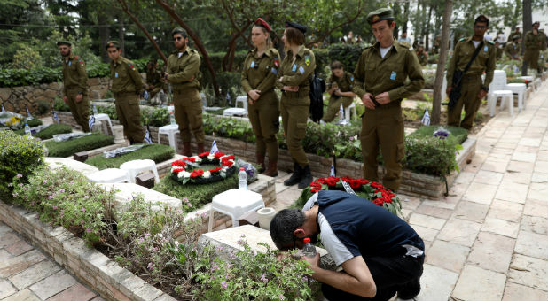 A man mourns over a grave during the Memorial Day for the Israeli fallen soldiers in the military cemetery in Mount Herzl