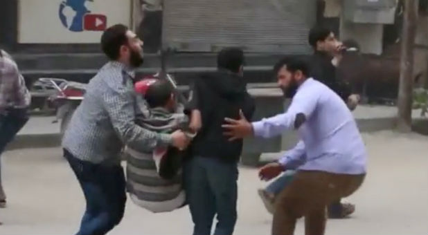 A still image taken from a video uploaded by the Ghouta Media Centre on April 30, 2017, purportedly shows a man being helped by others during a protest against fighting between rebel factions, said to be shot in Eastern Ghouta, Damascus, Syria