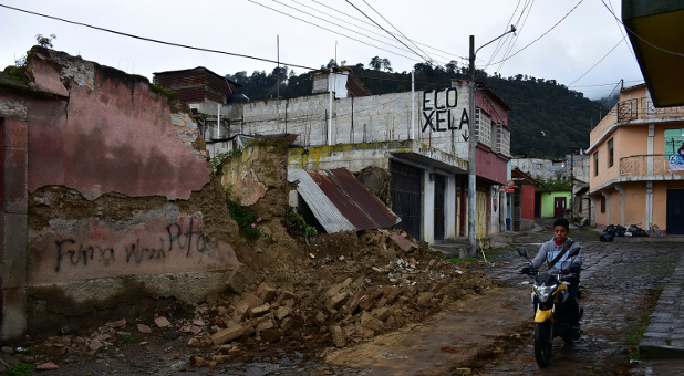 A resident rides a scooter past a collapsed wall after an earthquake in Quetzaltenango, Guatemala.
