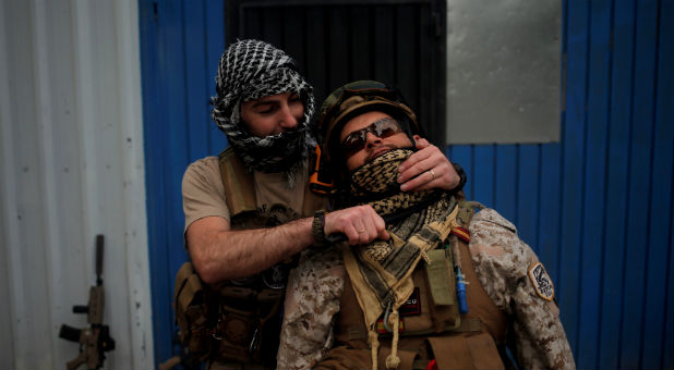 A player depicting an Islamic State militant holds a fake knife as he simulates a beheading of a player depicting a soldier from the U.S.-led coalition forces during an airsoft game.