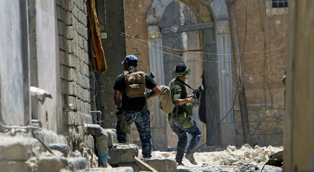A member of the Iraqi Federal Police (R) throws a hand grenade against Islamic State militants at the frontline in the Old City of Mosul, Iraq.