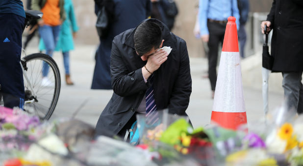 A man reacts next to floral tributes for the victims of the attack on London Bridge and Borough Market near the scene of the attack, London.