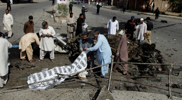 Police and rescue officials cover a body after a blast in Quetta, Pakistan.