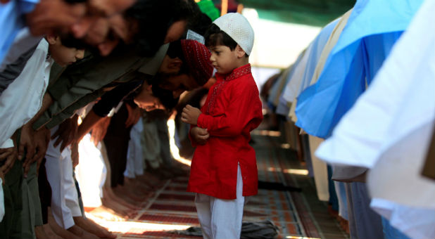 A boy stands among people offering last Friday prayers during the holy month of Ramadan in Rawalpindi, Pakistan.