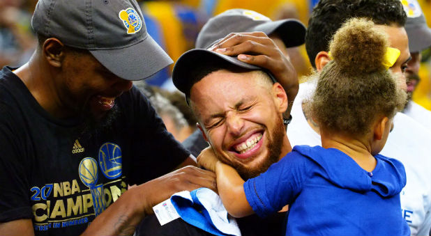Golden State Warriors forward Kevin Durant and guard Stephen Curry celebrate with Curry's daughter Riley after defeating the Cleveland Cavaliers 129-120 in game five of the NBA Finals.
