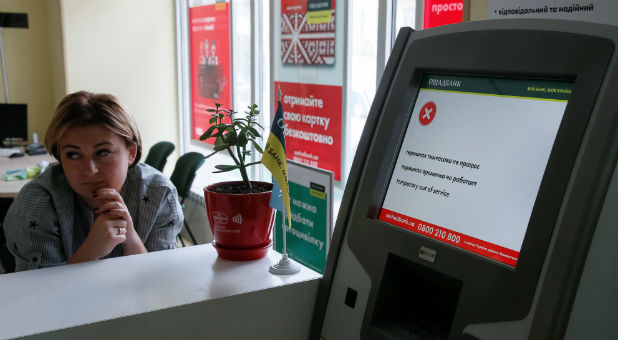An employee sits next to a payment terminal out of order at a branch of Ukraine's state-owned bank, Oschadbank, after Ukrainian institutions were hit by a wave of cyberattacks earlier in the day.