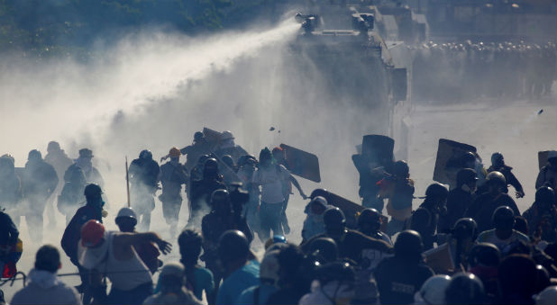 Demonstrators clash with riot security forces while rallying against Venezuela's President Nicolas Maduro in Caracas, Venezuela.