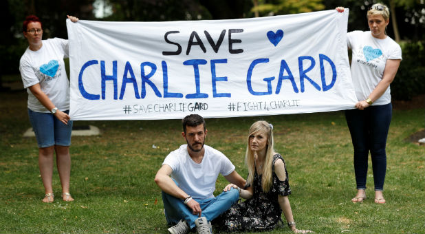 The parents of critically ill baby Charlie Gard, Connie Yates and Chris Gard, pose for photographers as supporters hold a banner before delivering a petition to Great Ormond Street Hospital, in central London, Britain.