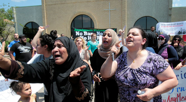 A group of women react as they talk about family members seized on Sunday by Immigration and Customs Enforcement agents during a rally outside the Mother of God Catholic Chaldean church in Southfield, Michigan.