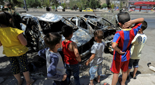 Children look at the wreckage of vehicles at a blast site in the Baytara traffic circle near the Old City of Damascus, Syria.