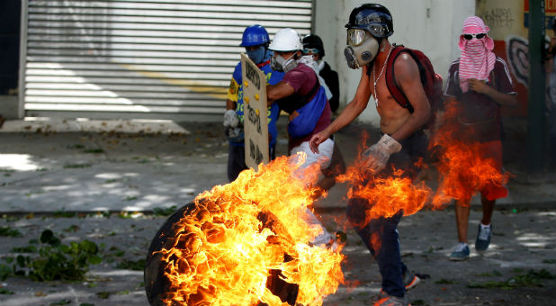 Demonstrators use a tire on fire to block a street at a rally during a strike called to protest against Venezuelan President Nicolas Maduro's government in Caracas, Venezuela.