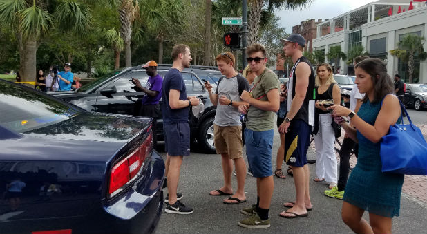 Bystanders wait at a perimeter set up by local police after reports of a man armed with a handgun holding hostages at a restaurant in downtown Charleston, South Carolina.