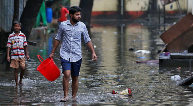 A man carrying a bucket walks through a water-logged neighborhood in Mumbai, India, Aug. 30, 2017.