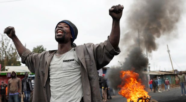 A supporter of opposition leader Raila Odinga gestures in front of burned barricade in Kibera slum in Nairobi, Kenya.