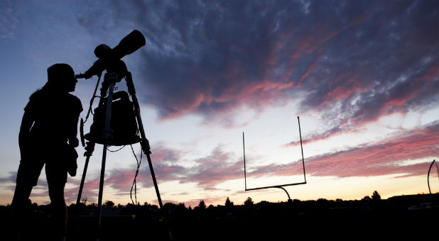 A woman looks through a telescope on the football field at Madras High School the evening before a solar eclipse in Madras, Oregon, U.S., Aug. 20, 2017.