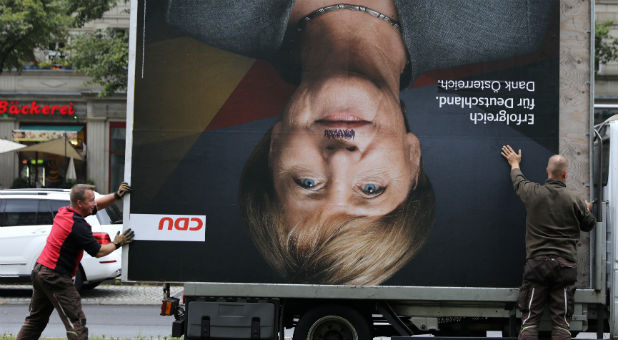 Workers remove an election campaign billboard showing Christian Democratic Union CDU party leader and German Chancellor Angela Merkel.