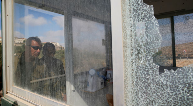 Israeli soldiers look into a security booth damaged during a shooting attack.