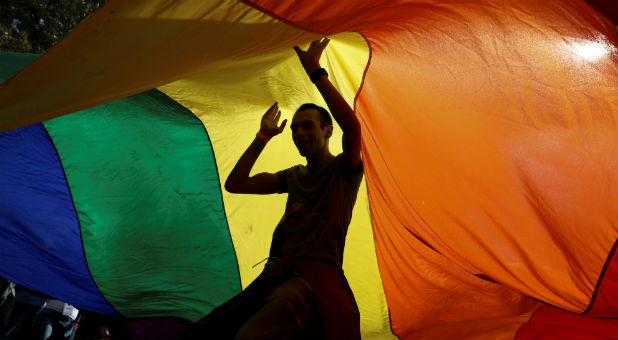 Participants dance under a rainbow flag during an annual LGBT (Lesbian, Gay, Bisexual and Transgender) pride parade.