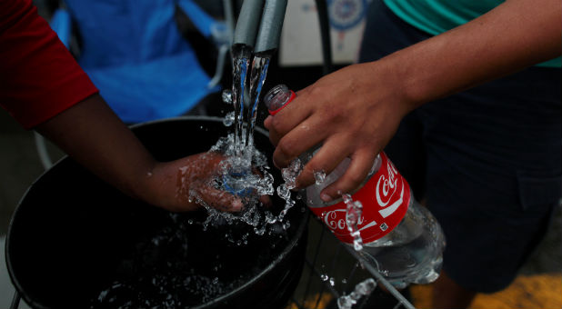Local residents fill up plastic bottles during a water distribution in Bayamon following damages caused by Hurricane Maria.