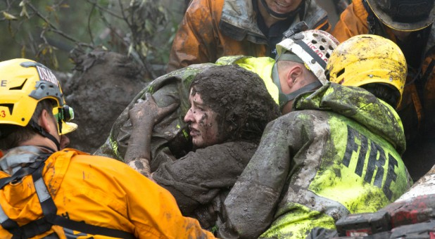 Emergency personnel carry a woman rescued from a collapsed house after a mudslide in Montecito, California.