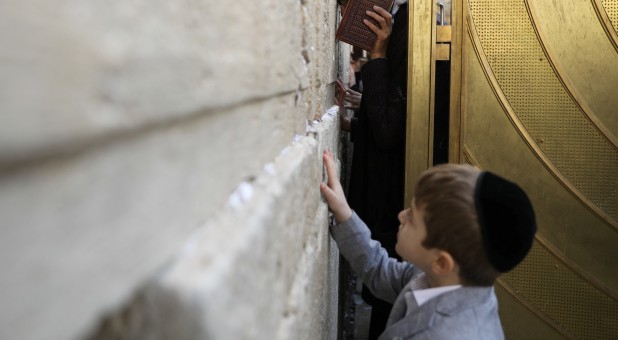 A child touches the Western Wall, Judaism's holiest prayer site, as a woman prays in the women's section of the site.