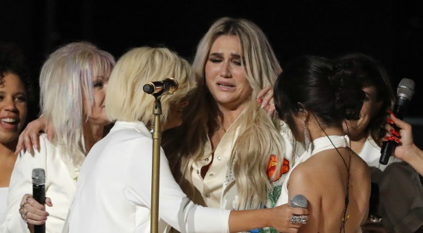 Kesha (C) is embraced by a multitude of singers after they performed