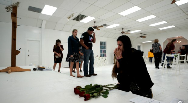 A woman prays in the First Baptist Church of Sutherland Springs where 26 people were killed in a shooting attack.