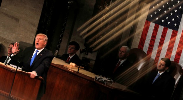 U.S. President Donald Trump and Vice President Mike Pence (C) are seen behind the reflection of a House chamber railing as Trump delivers his State of the Union address.