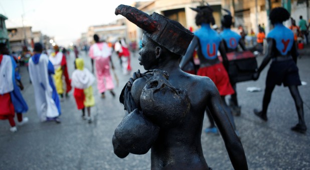 A reveller carrying two skulls parades along a street at the Carnival of Port-au-Prince, Haiti.