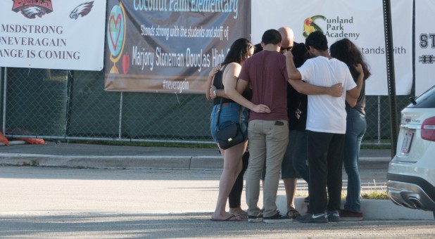 People gather for an impromptu prayer circle, in front of the building where the shooting took place, as students and parents attend a voluntary campus orientation at the Marjory Stoneman Douglas High School.