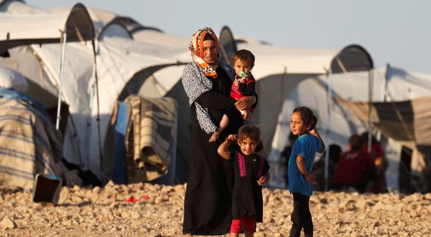 A woman and her children stand outside their tent at a refugee camp for people displaced by fighting between the Syrian Democratic Forces and Islamic State militants.
