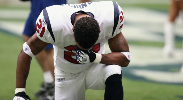 A football player kneels in prayer.