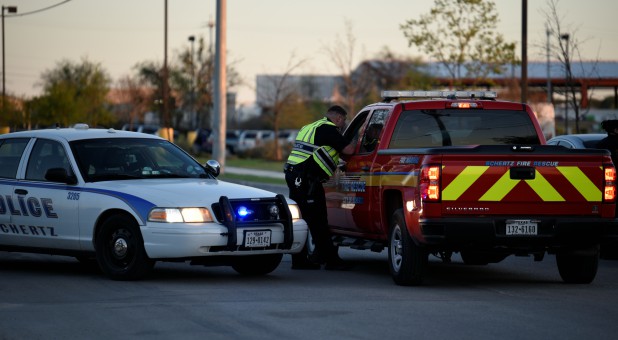 A Schertz Police officer speaks to a member of Schertz Fire Rescue on Doerr Lane near the scene of a blast at a FedEx facility in Schertz, Texas.