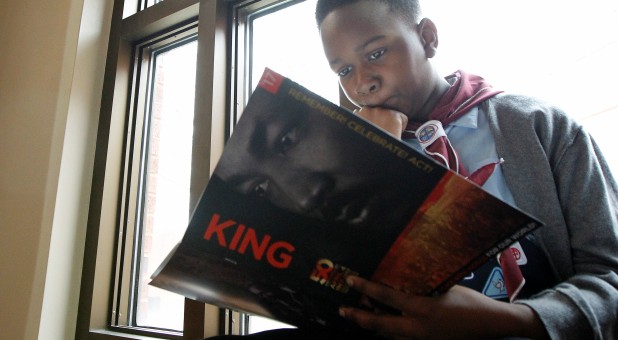 Nine-year old Micah Brown looks over the King program as he sits along a window during the Martin Luther King Jr. Commemorative Service at Ebenezer Baptist Church in Atlanta, Georgia.